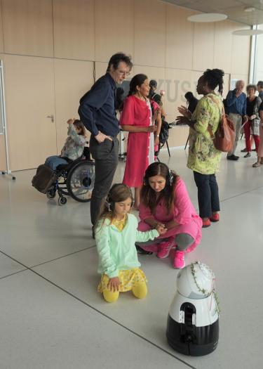 A group of people with a child approaching a small robot